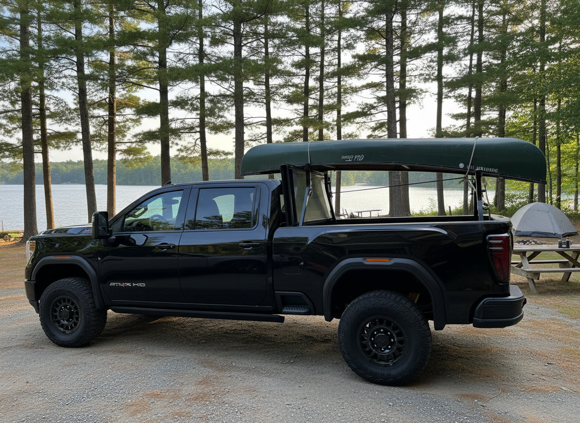 Black pickup truck with a canoe on tuckrack rack camping